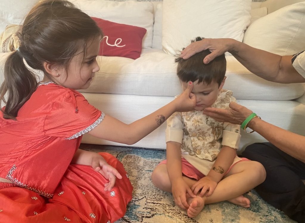 Girl blesses her brother by putting her thumb on his forehead.