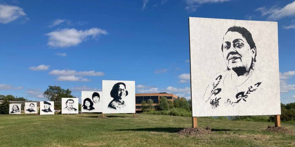 Large portraits of immigrants who live in Eden Prairie line Technology Drive at Purgatory Creek Park as part of a First Persons Plural (We) art installation by artist Cadex Herrera. Pictured, front to back, are Juana Luna Monroy, Shanti Shah, Khamphet Noy and Dasia, Masaood Yunus, Olof Indridadottir, Marcos Mejia, and Sylvia Mejia. (Photo by Mark Weber)