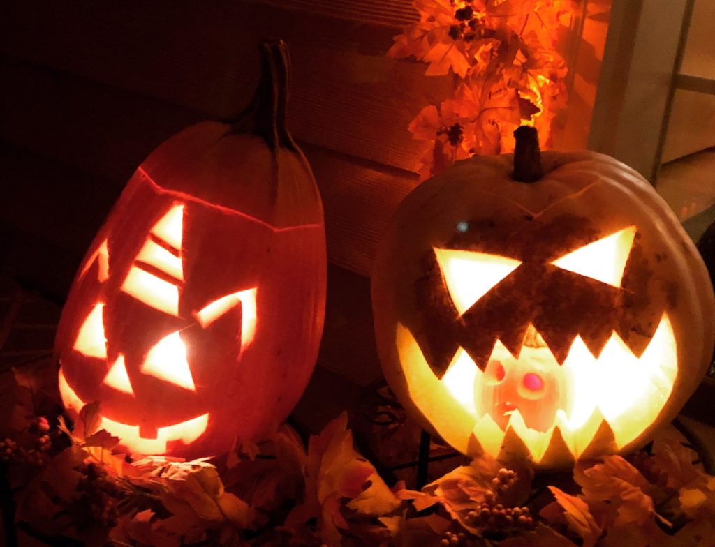 Two scary jack-o-lanterns glow from on a dark night.