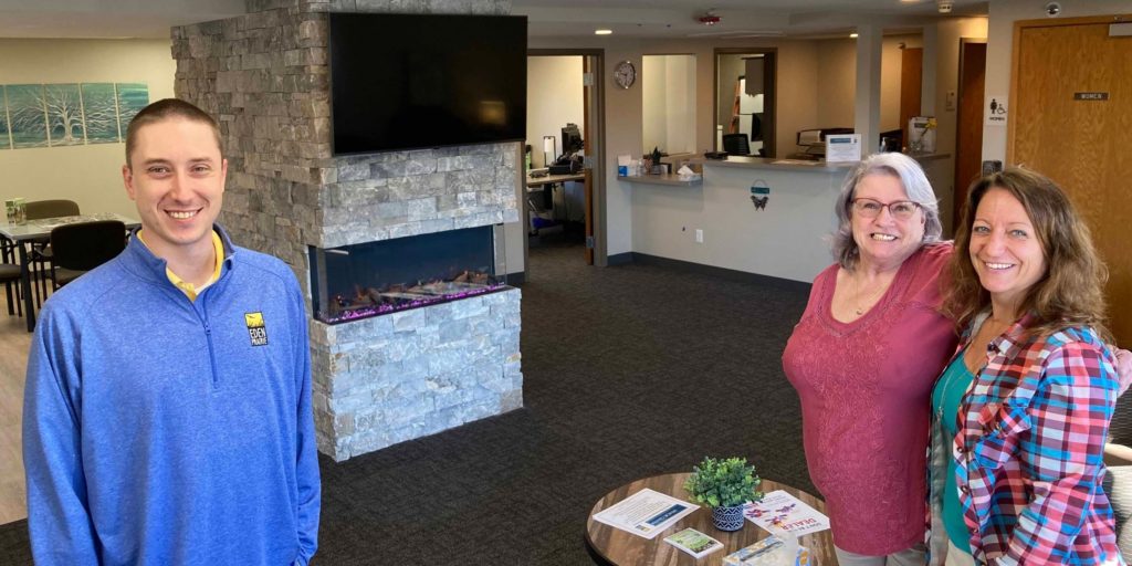 Eden Prairie Senior Center user Beth Lapp, second from right, joins Recreation Specialist Josh Rockey and Senior Center Supervisor Sue Bohnsack for a photo in the new fireside lounge area. Photo by Mark Weber