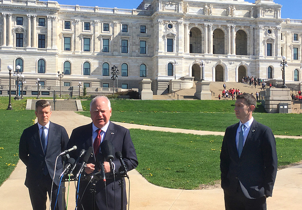 Gov. Tim Walz, center, speaking at Monday's press conference, with House Majority Leader Ryan Winkler, left, and Senate Majority Leader Jeremy Miller, right. MinnPost photo by Peter Callaghan