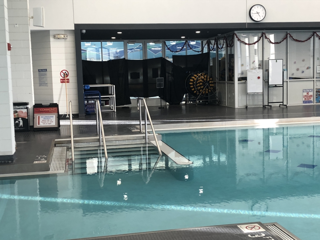 empty swimming pool with steps and privacy curtains over windows