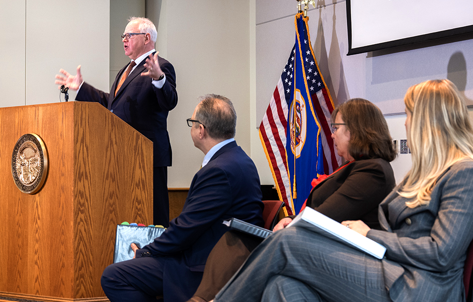 Gov. Tim Walz speaking at Monday's press conference as, from left, Management and Budget Commissioner Jim Schowalter, state economist Laura Kalambokidis, and Assistant Commissioner Ahna Minge, look on. MinnPost photo by Tom Olmscheid