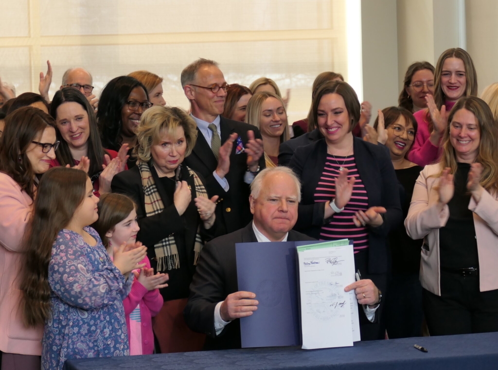 Gov. Tim Walz holds up a signed copy of the Protect Reproductive Options act during a ceremonial bill signing on Jan. 31 at the state Department of Revenue. Photo by Max Nesterak/Minnesota Reformer