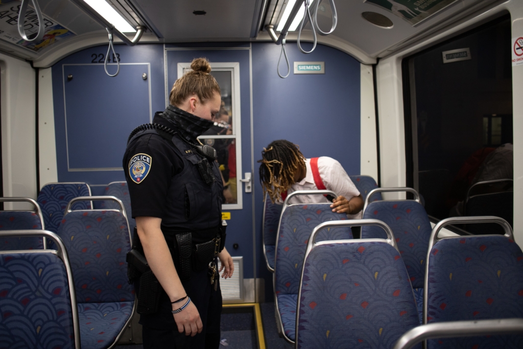 July 16, 2021-St. Paul: A Metro Transit Police officer rouses a passenger who was asleep as the train goes out of service at Union Depot Station. A pandemic-induced ridership decreased has spurred an increase in safety and quality-of-life complaints on Metro Transit's light rail and rapid bus network. Henry Pan/Minnesota Reformer