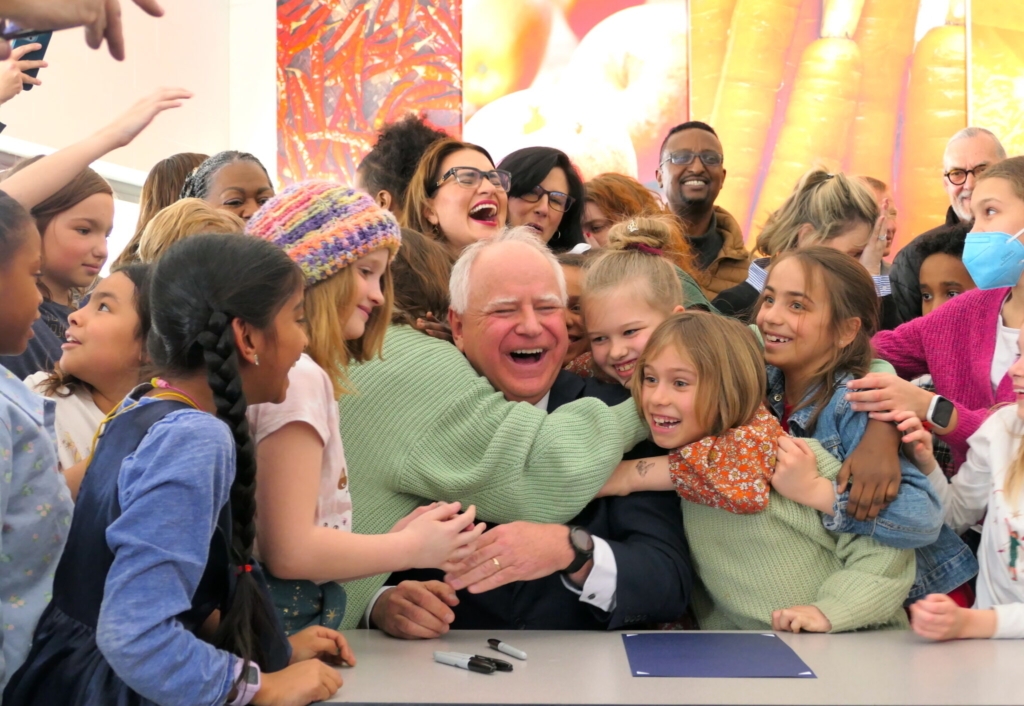 Students from Webster Elementary School in northeast Minneapolis hugged Gov. Tim Walz after he signed a bill to provide free breakfast and lunch to Minnesota students. Photo by Michelle Griffith/Minnesota Reformer
