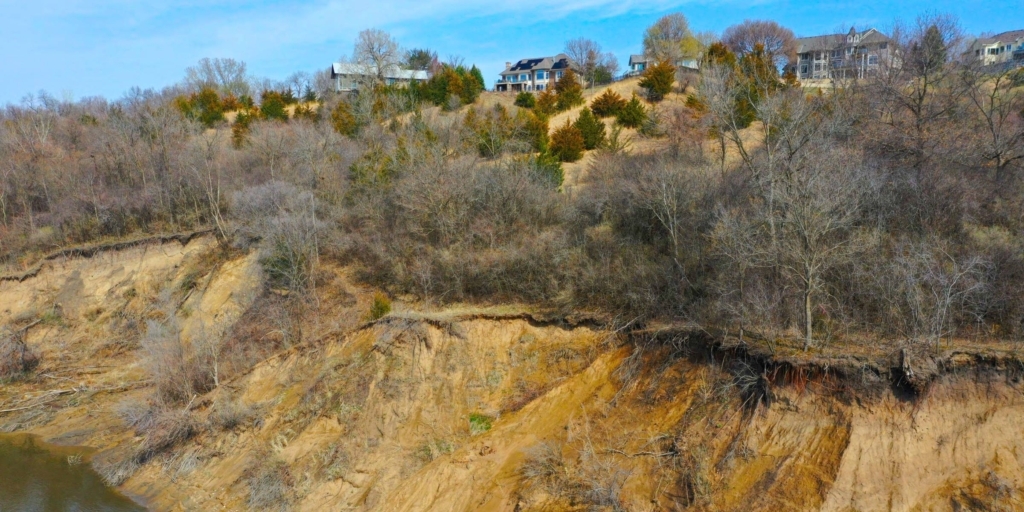 bluff with exposed dirt, trees and houses atop it