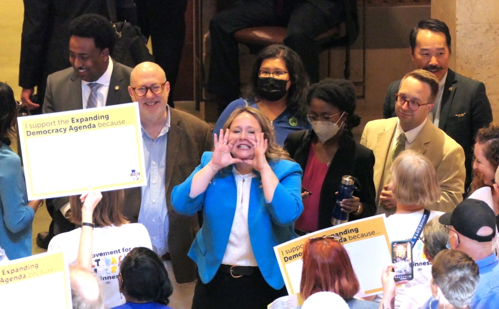 Rep. Emma Greenman, DFL-Minneapolis (center), chanted with supporters of the Democracy for the People Act outside the House chambers on Thursday, April 13. Photo by Michelle Griffith/Minnesota Reformer