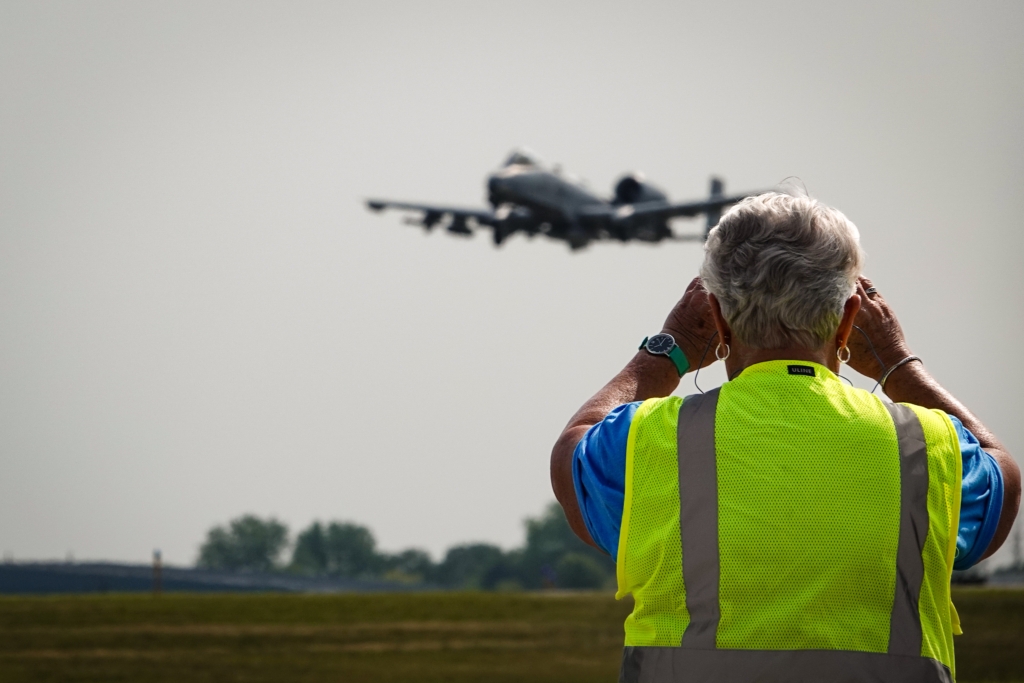 A Wings of the North volunteer uses binoculars to watch a A-10 land at Flying Cloud Airport at the Air Expo on Saturday, July 22.
