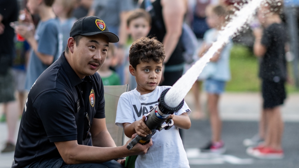Jiovani Burns tests the fire hose at EP Fire Station 2 on Thursday, assisted by firefighter Zachary Tang. All four city stations were open for Neighborhood Night at the Fire Station. Photos by Jeremy Peyer