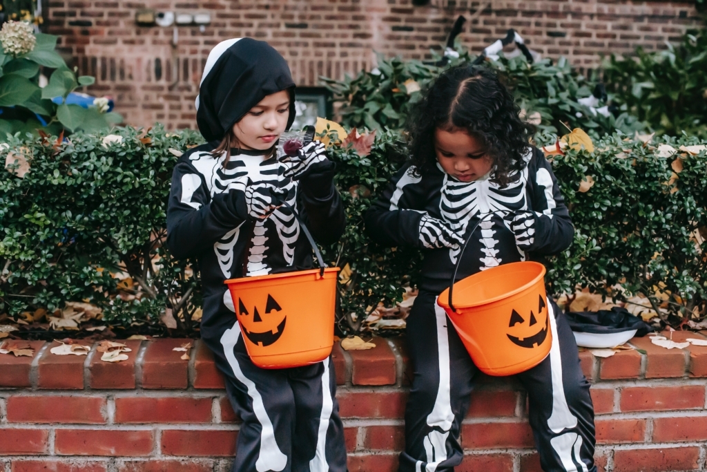 Two girls dressed as skeletons looking in their trick and treat buckets