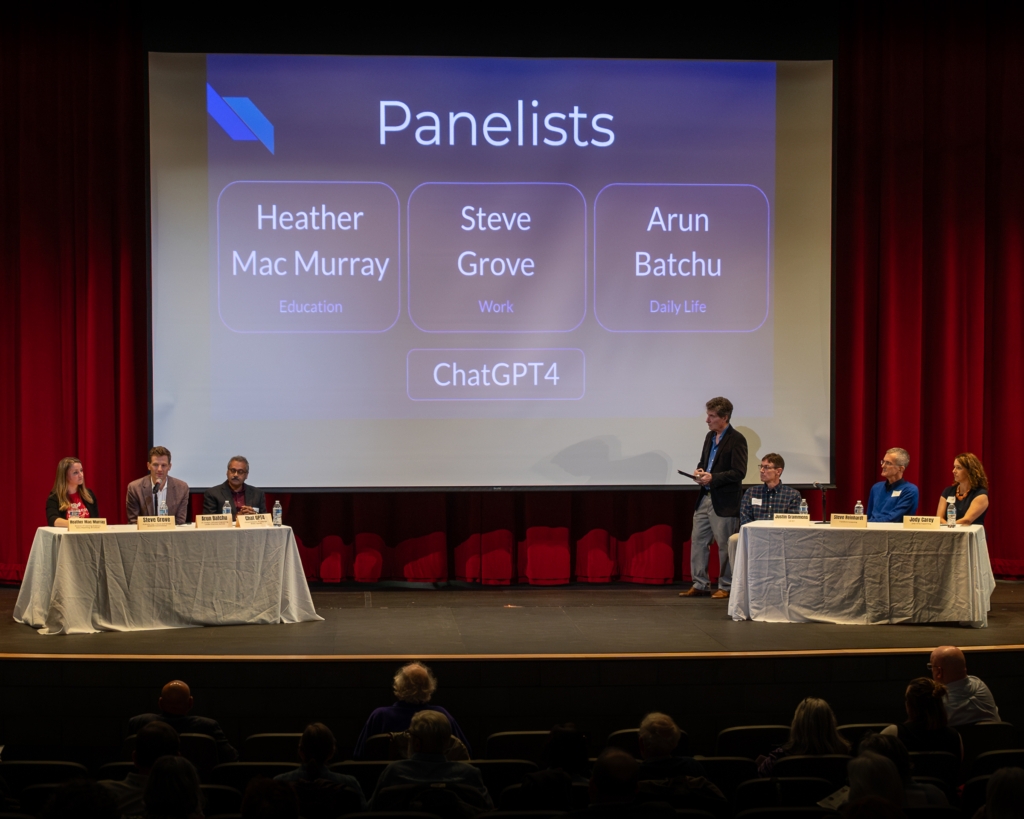 AI town hall panelists on stage, Central Middle School Performing Arts Center