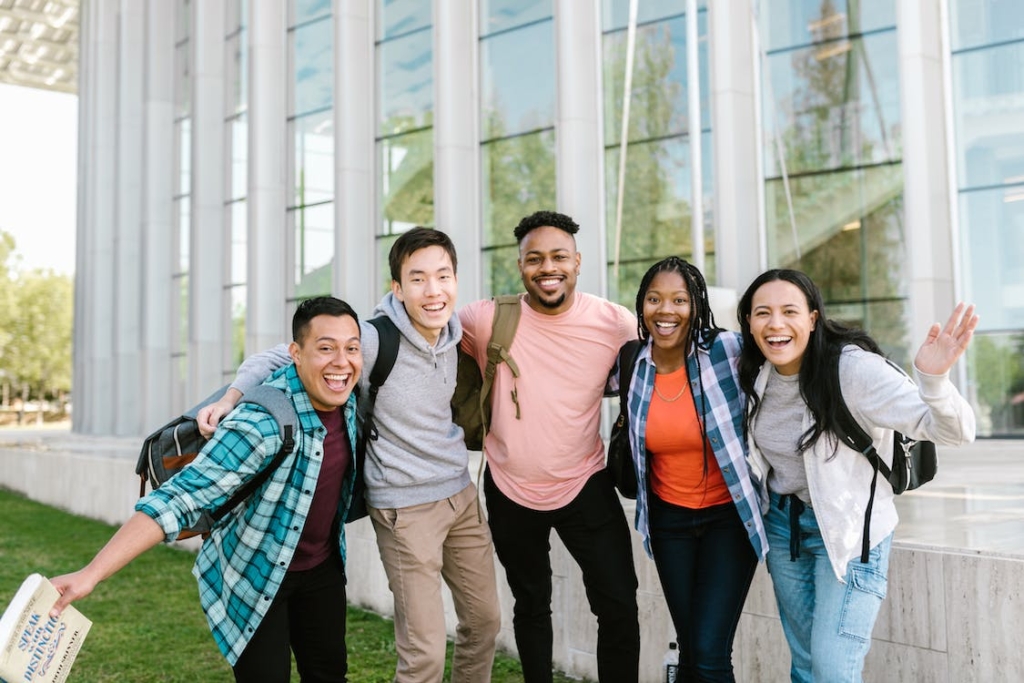 Five happy college students in front of a building. Photo by RDNE Stock Project / Pexels