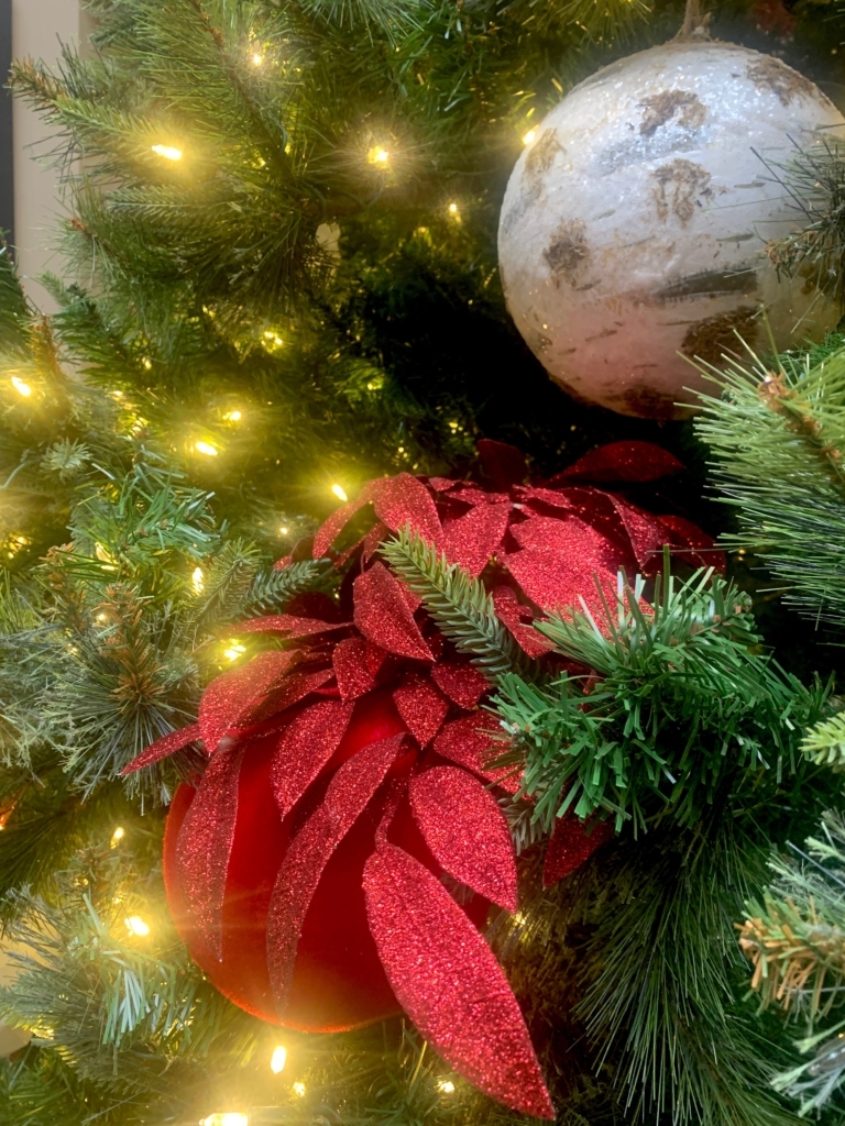 Red poinsettia and white Christmas tree with white twinkle lights.