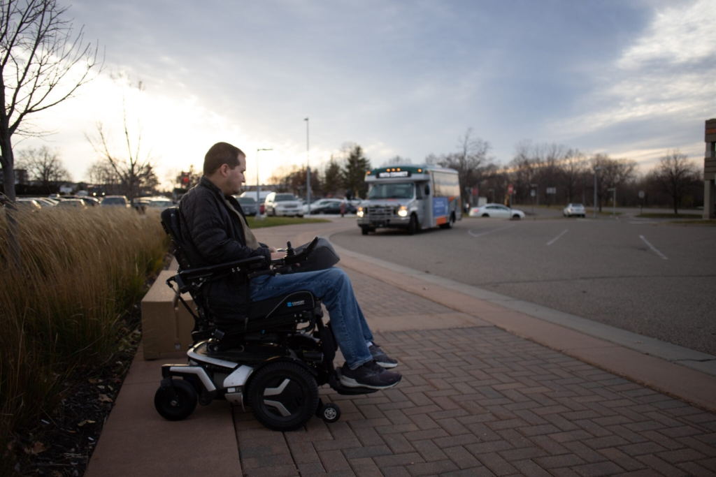 November 16, 2023-Burnsville, Minnesota, USA: Andrew Landon waits for an MVTA Connect bus to pull up at Burnsville Transit Station. Public transit agencies seeking to mimic Uber and Lyft service are seeing ridership gains. (H. Jiahong Pan/Minnesota Reformer)