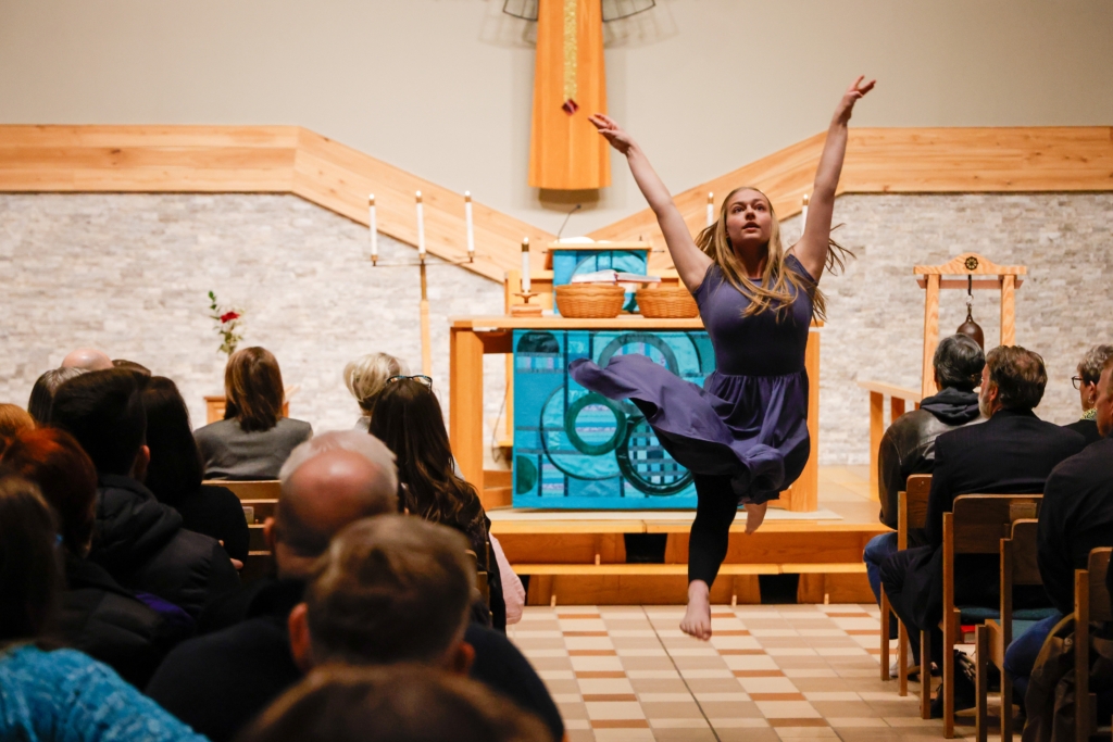 teenage female dancer performs a leap in aisle of church in front of altar