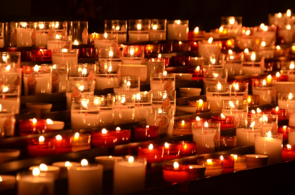 dozens of votive candles lit with a dark background