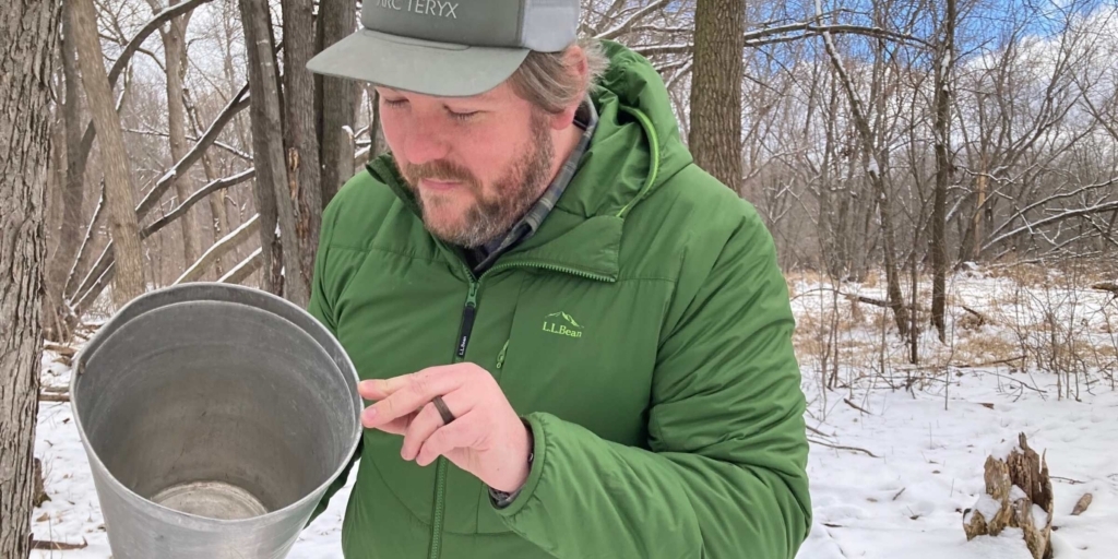 Max Melby’s role as the new supervisor of the Staring Lake Outdoor Center is far-ranging and includes outdoor-education programs. One recent program had people learning about maple syruping via the handful of buckets used to collect tree sap that is processed into syrup. Photo by Mark Weber