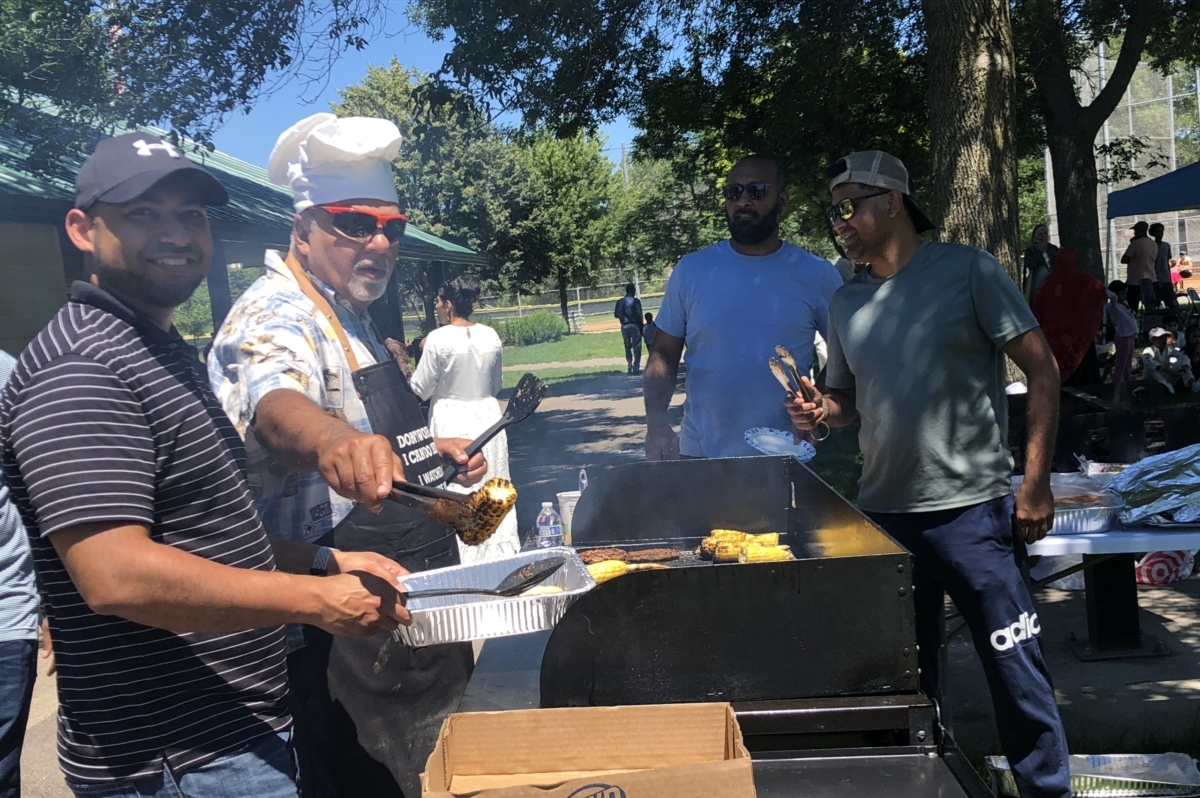 Grill chef Nazir Bagha of Eden Prairie serves up chicken to 2003 EPHS graduate Faraz Currimbhoy at Quba Islamic Center's Eid picnic and barbecue. Photo by Joanna Werch Takes