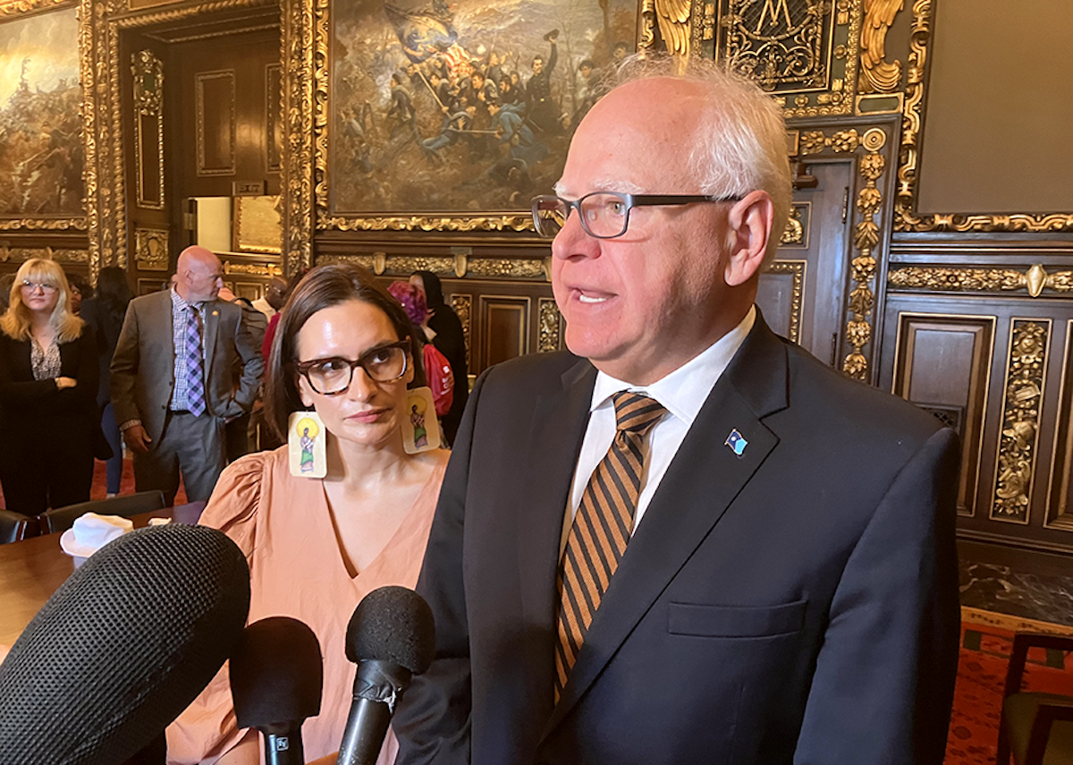Minnesota Gov. Tim Walz speaking before microphones with Lt. Gov. Peggy Flanagan