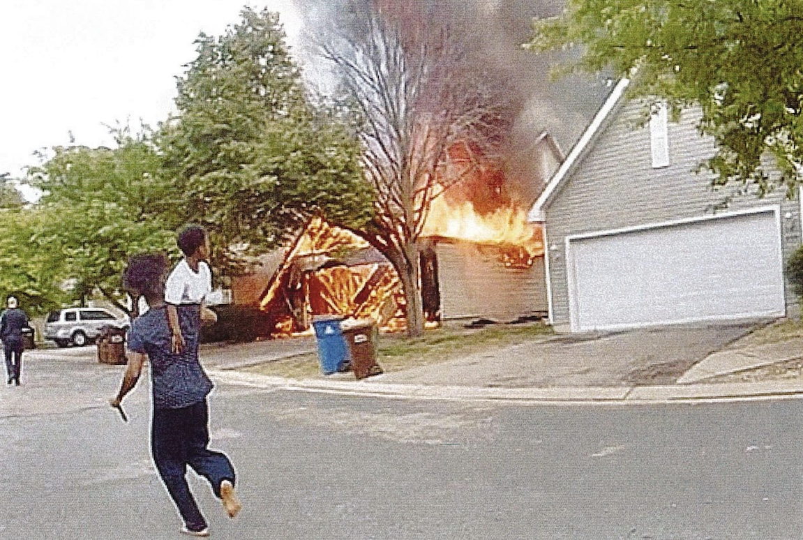 A man holds a child near the burning townhome in the 8500 block of Cardiff Lane, Eden Prairie, on May 31. Photo from federal affidavit