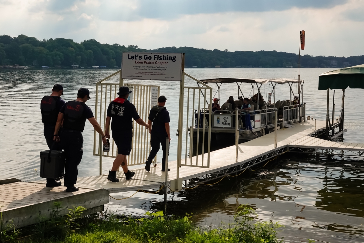 Firefighters walk down the dock to join the children and crew for the "Hooks and Ladders" event on Lake Riley.