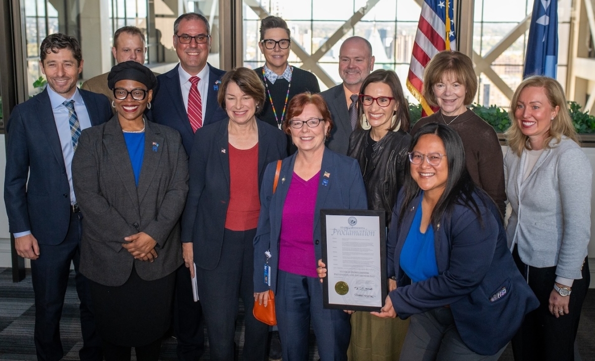 Hennepin County officials and state and federal leaders gather at an Oct. 15 press conference in Minneapolis to announce Hennepin County’s certification for effectively ending veteran homelessness. Back row, from left: Minneapolis Mayor Jacob Frey; Hennepin County Veterans Services Director Neil Doyle; District 7 Commissioner Kevin Anderson; Hennepin County senior social worker Taya Kaufenberg; Minnesota Department of Veterans Affairs Commissioner Brad Lindsay; U.S. Sen. Tina Smith; and District 6 Commissioner Heather Edelson. Front row, from left: District 4 Commissioner Angela Conley; U.S. Sen. Amy Klobuchar; District 5 Commissioner Debbie Goettel; Lt. Gov. Peggy Flanagan; and Hennepin County Board Chair Irene Fernando. Photo courtesy of Hennepin County
