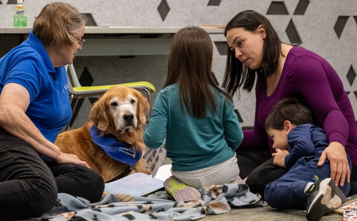 Handler Monica Vogel and her therapy dog Bala, a golden retriever, sit on the left, while Jamie Levesque and her children, Maddie and Ethan, are on the right during the PAWS to READ event at Eden Prairie Library. Photos by Jeremy Peyer