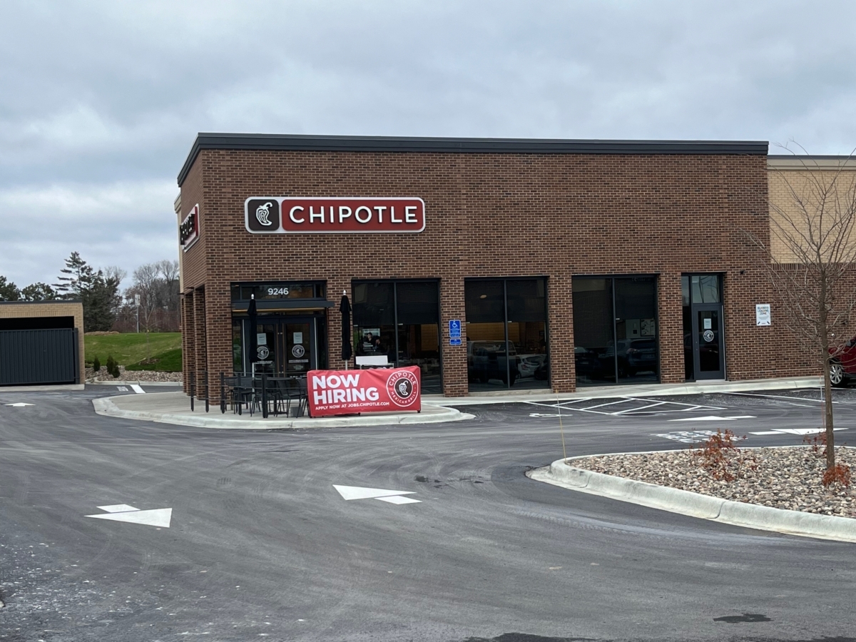 Chipotle restaurant building with now hiring sign in front and drive-through lane arrows on road