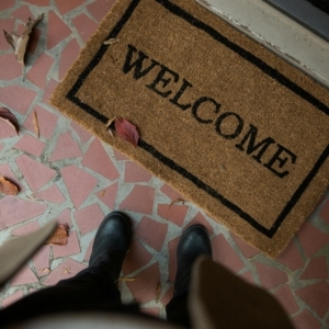 person wearing boots standing near a doormat