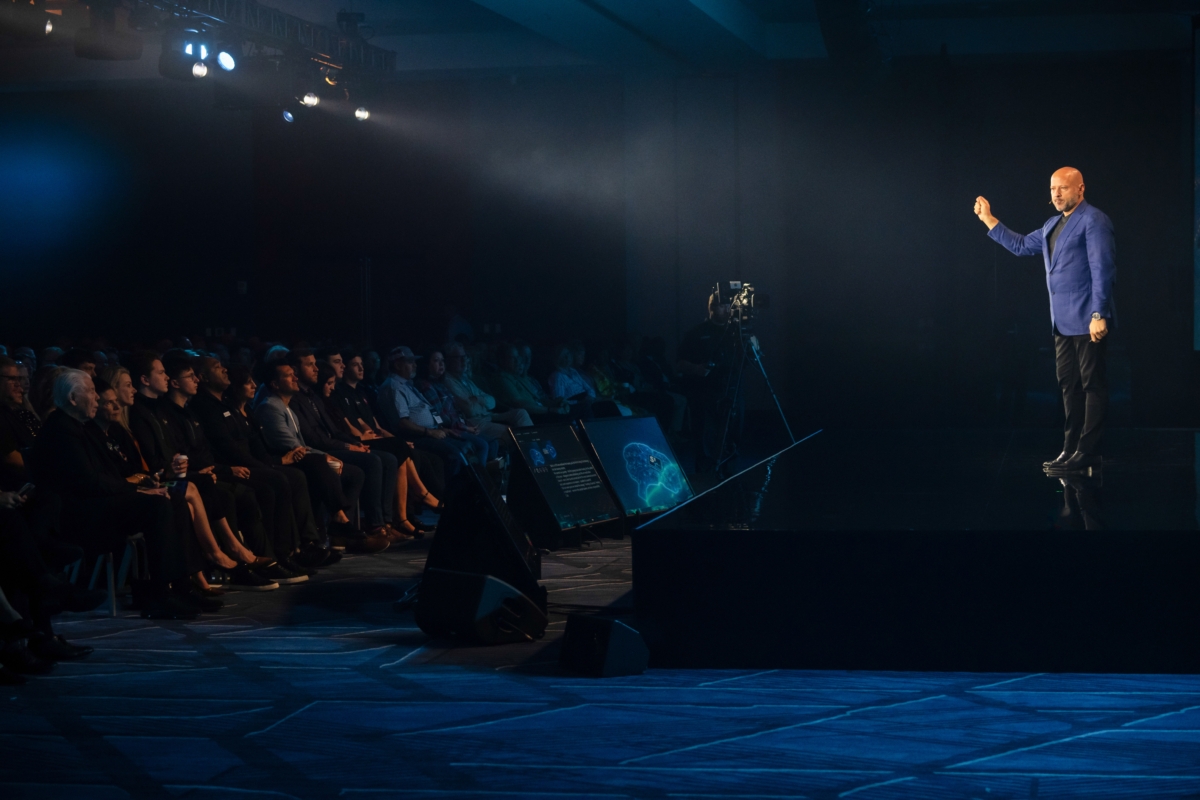 man in blue jacket presents from stage to audience