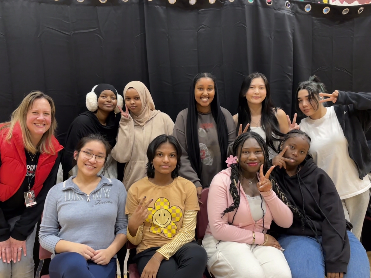 Several high school members of a Kpop Club and their advisor pose for a photo.