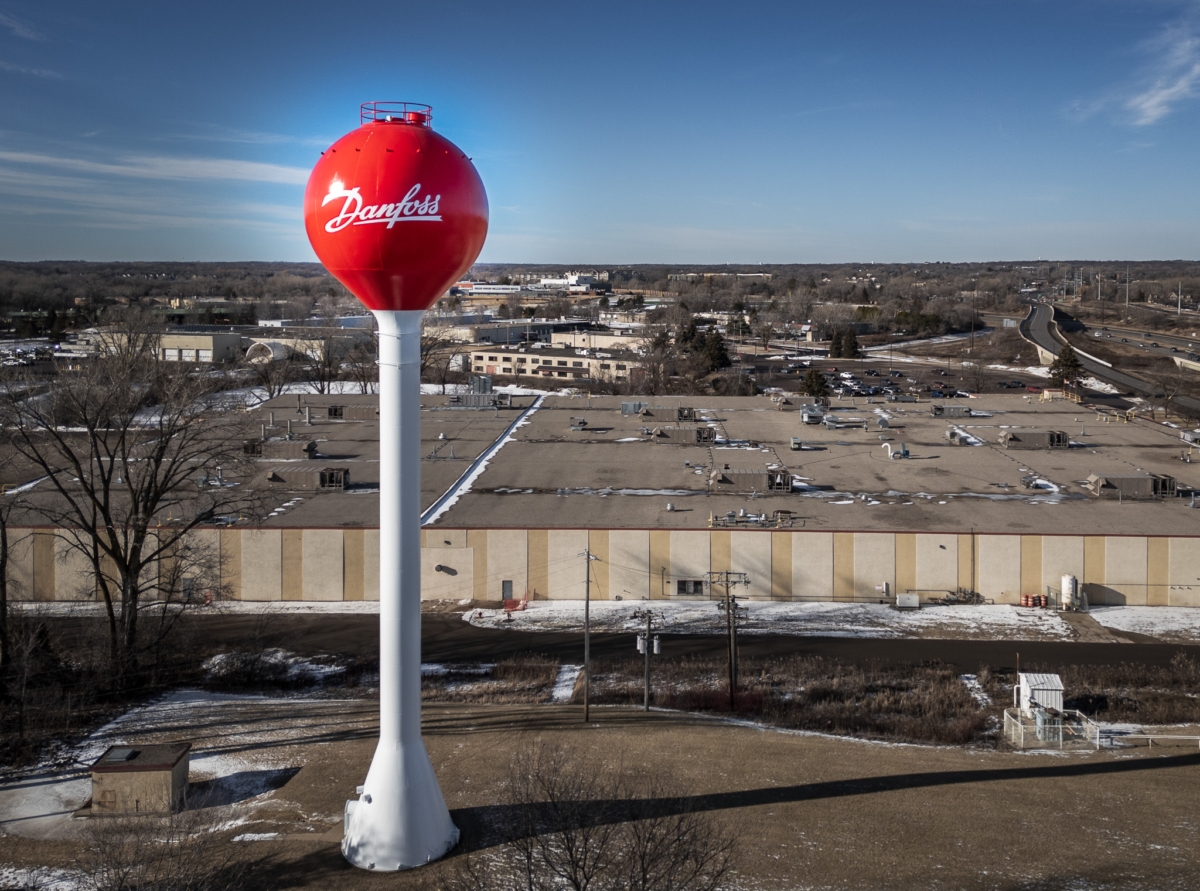 An aerial image of a red water tower with word "Danfoss" on it, with an industrial building in the background.