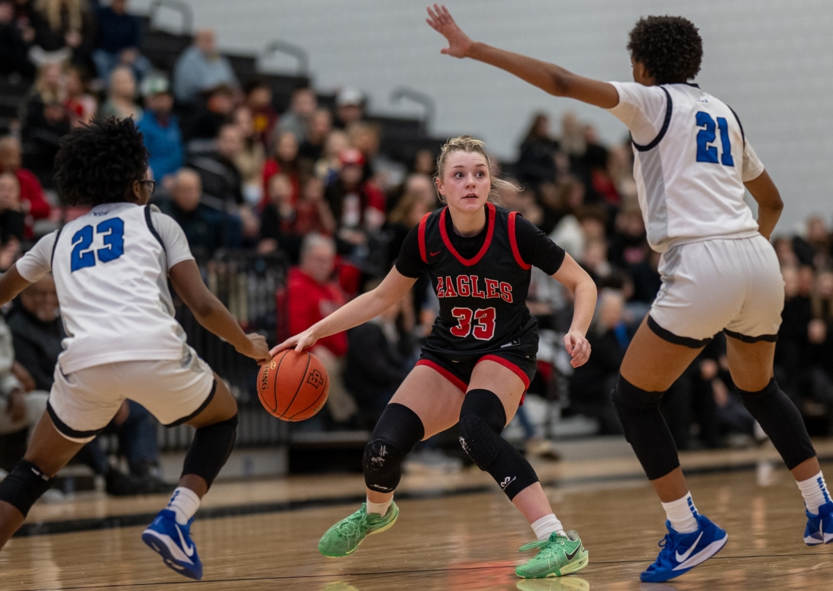 Eden Prairie girls basketball senior guard Tori Schlagel dribbles a ball while being defended by two Hopkins players.