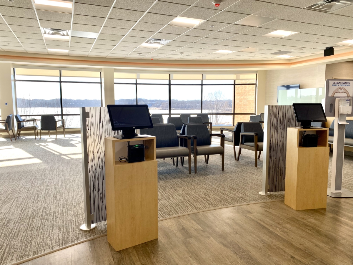 chairs and computer stands in medical office waiting area with wall of windows open to water view