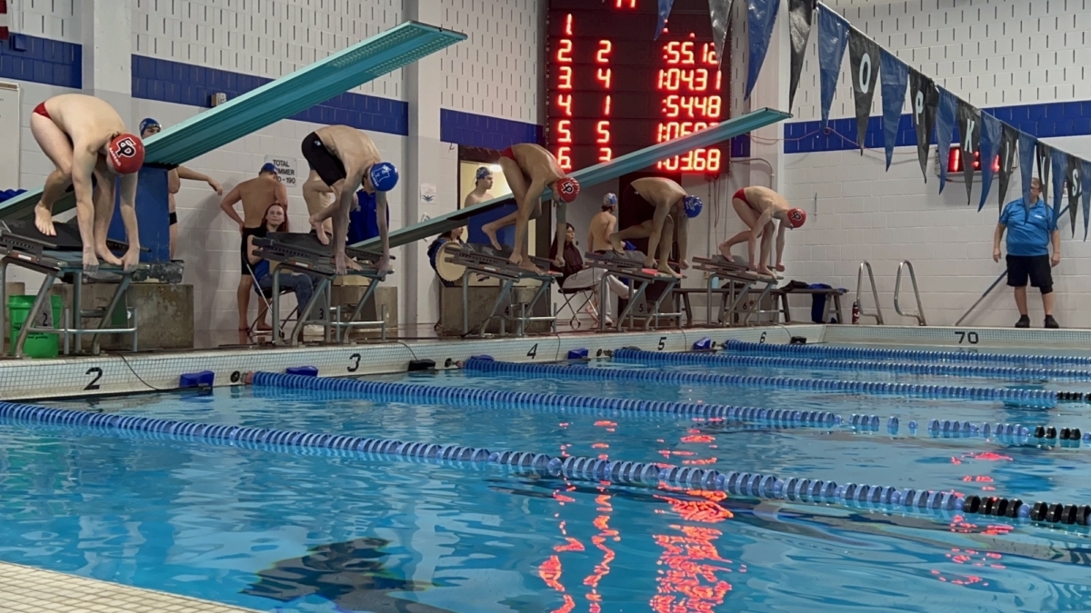 Finn Aaberg, Eshaan Salunke, and Will Cutting on the blocks for the varsity 100 free. Photo by Nico Allen