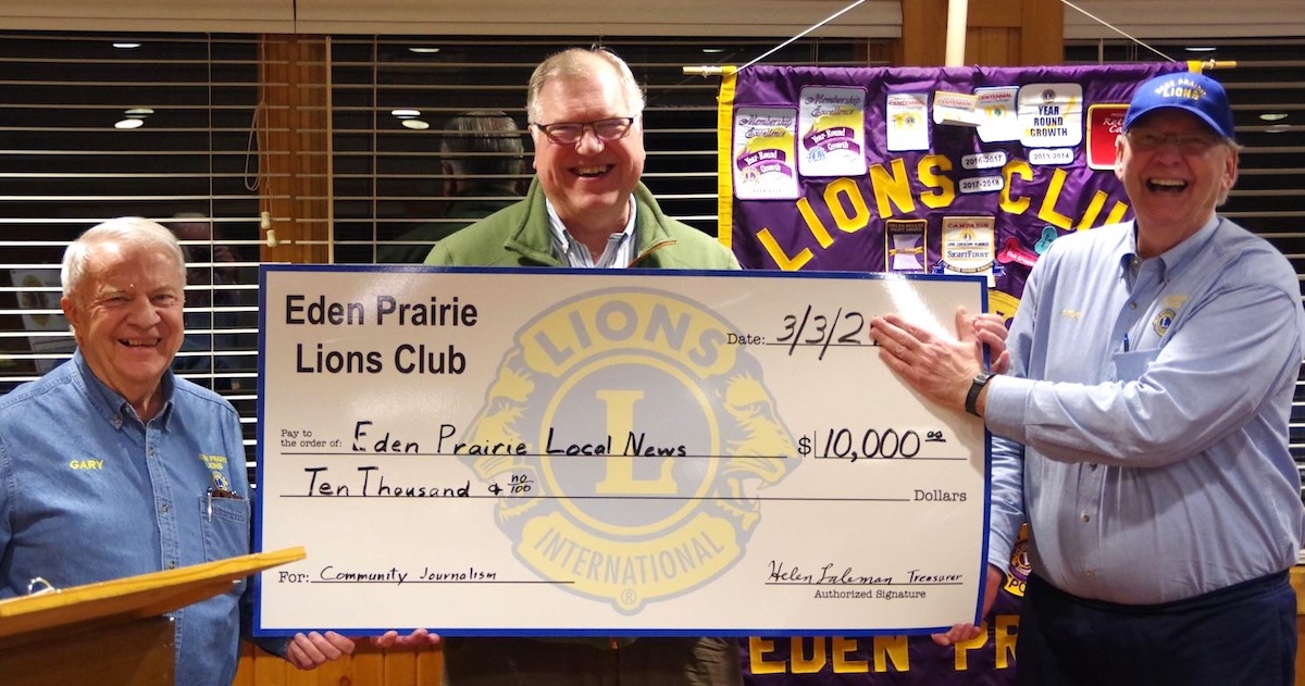 Gary Watkins, first vice president of the Eden Prairie Lions Club, left, and Steve Lipschultz, the club’s president, right, present a $10,000 ceremonial check to Eden Prairie Local News Publisher Steve Schewe, center, during the club’s meeting on Monday, March 3.