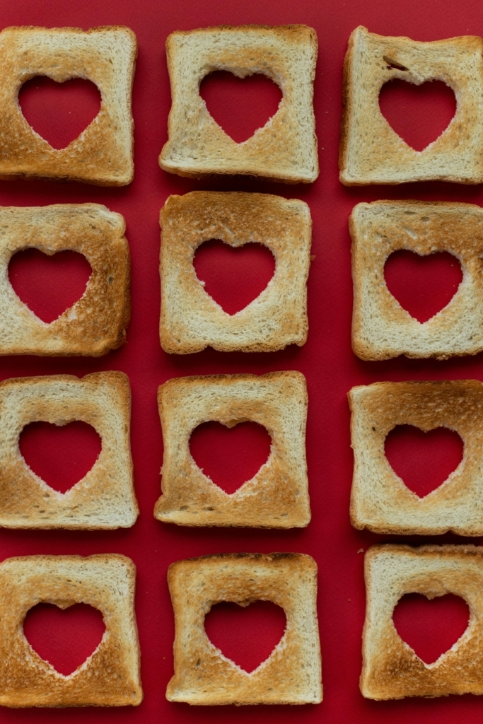 Several pieces of toast with hearts cuts out of each.