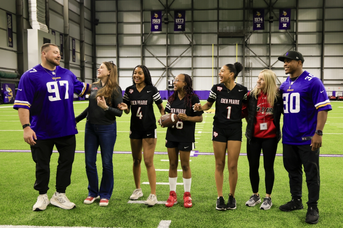Football players pose with student athletes and coaches.