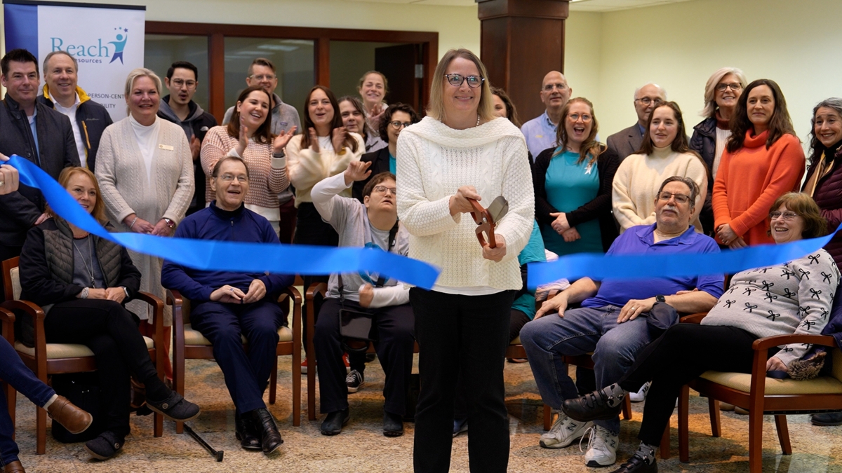 woman in white sweater cutting ribbon