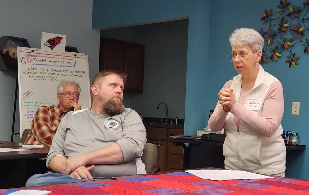 Scott Schluter, left, and Wilk Wilkerson look on as Melinda Voss talks with a small group attending a Braver Angels open house Monday, April 28, at the Willmar Area Community Foundation.
