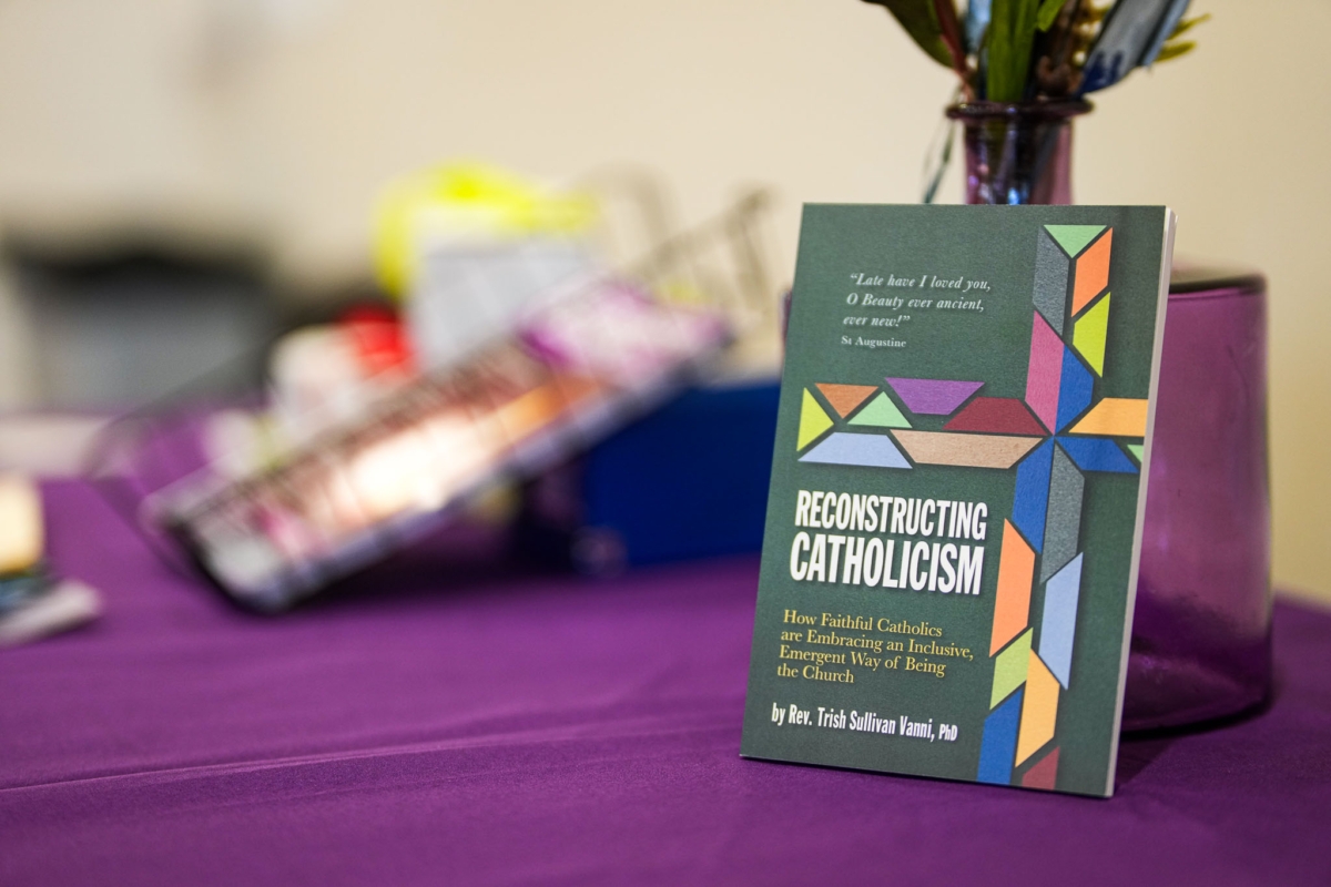 Cover of book titled "Reconstructing Catholicism" by Rev. Trish Sullivan Vanni on table with purple tablecloth.