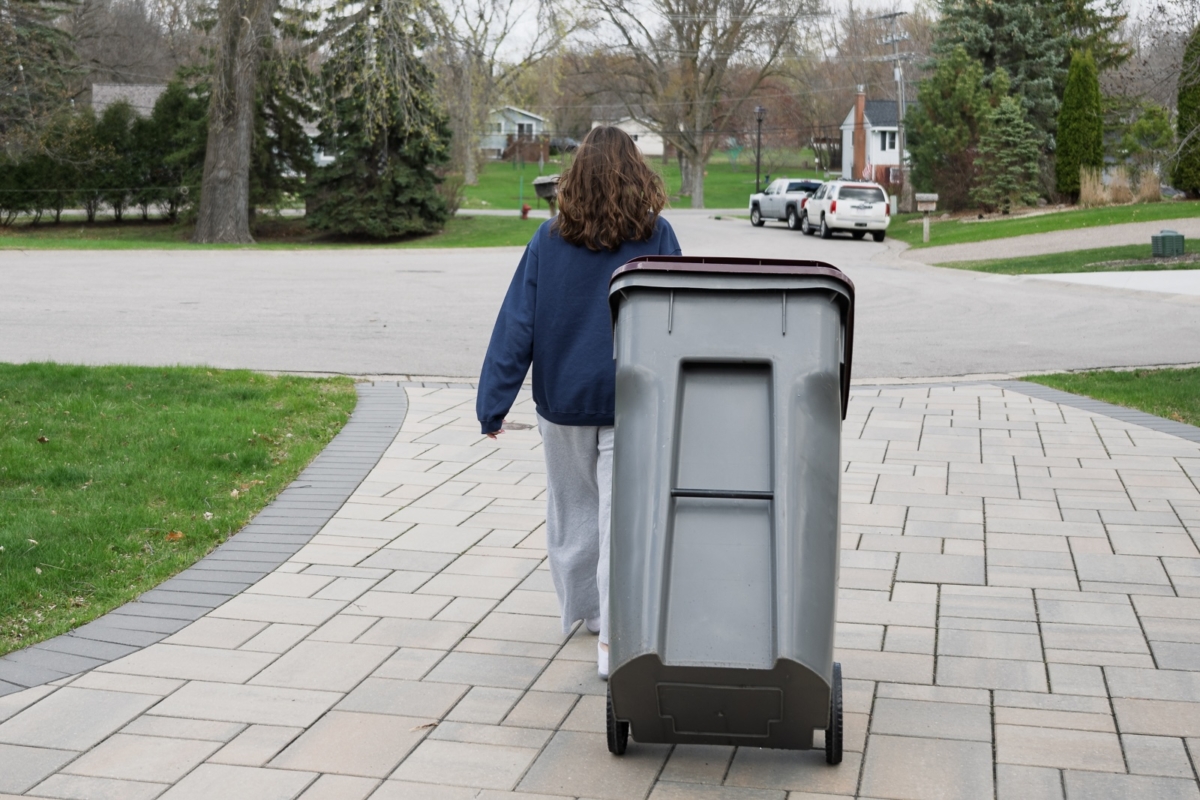 A resident brings a recycling bin to the curb outside her Eden Prairie home. Recyclables collected curbside are sent to processing facilities in Minneapolis, Shakopee, or Inver Grove Heights, depending on the waste service provider.