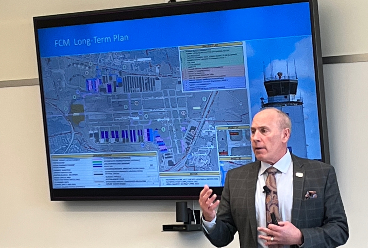 MAC CEO Brian Ryks stands in front of a screen displaying a map of FCM Airport long-term plan