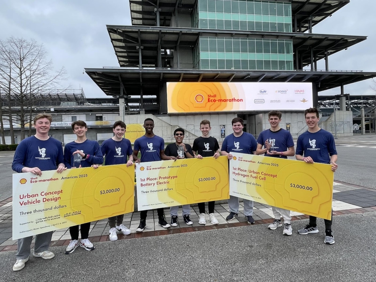 A group of students in blue shirts from St. Thomas Academy display yellow signs indicating their prize winnings from Shell Eco-marathon