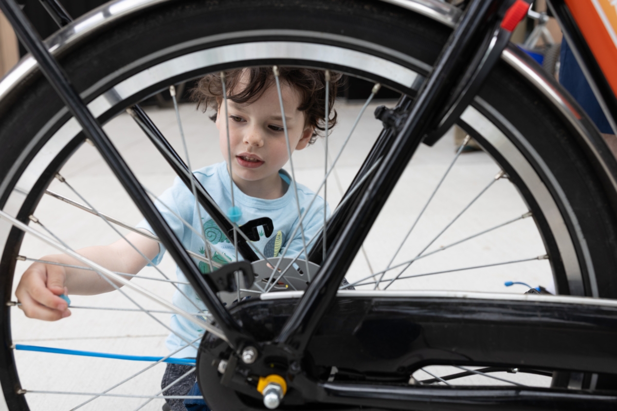 young boy behind spokes of bicycle wheel