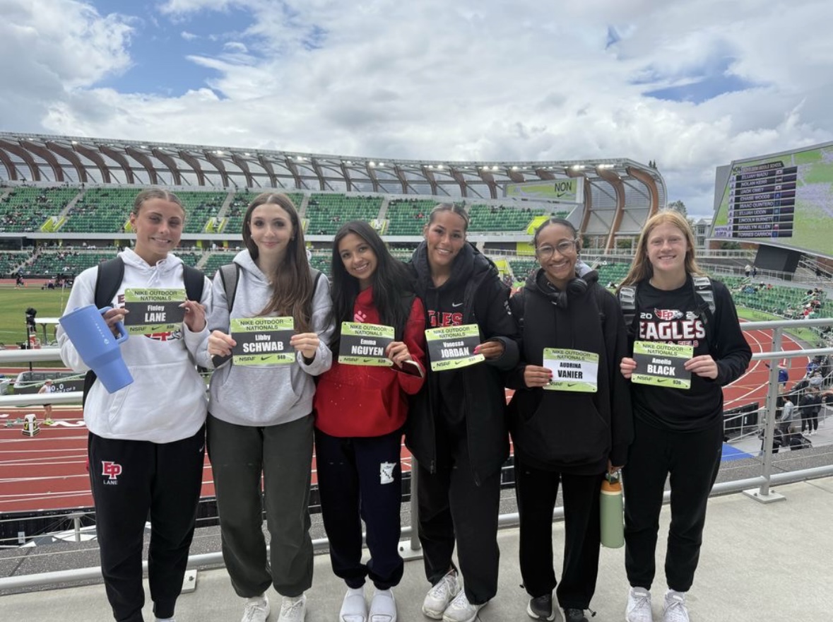 6 young women hold signs with their names near an outdoor track