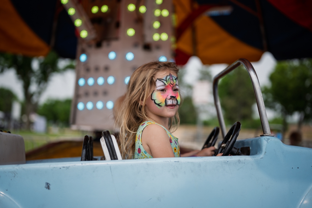 Maddie Jones, her face painted, looked out as her car rounded the track on a carnival ride during Schooner Days at Round Lake Park.