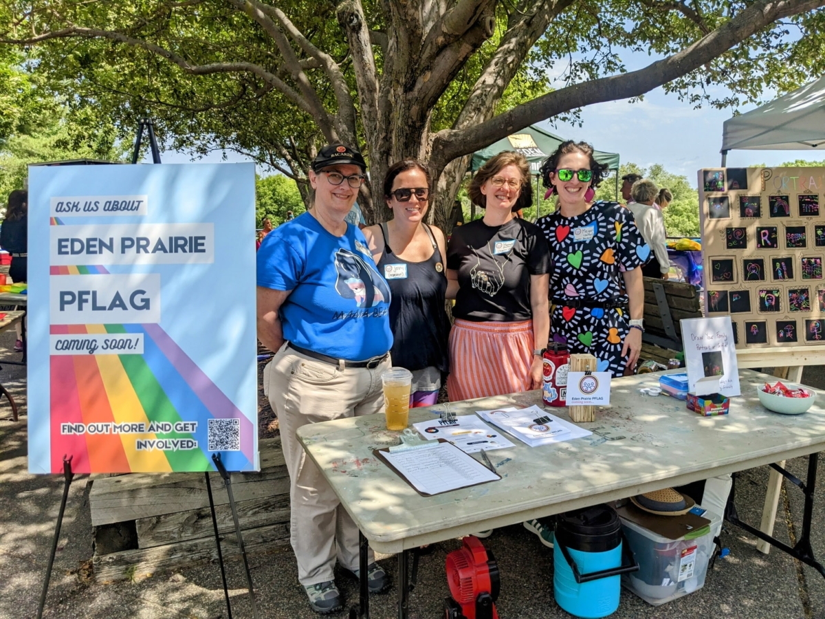 Four women standing behind PFLAG table at Eden Prairie's Party for Pride