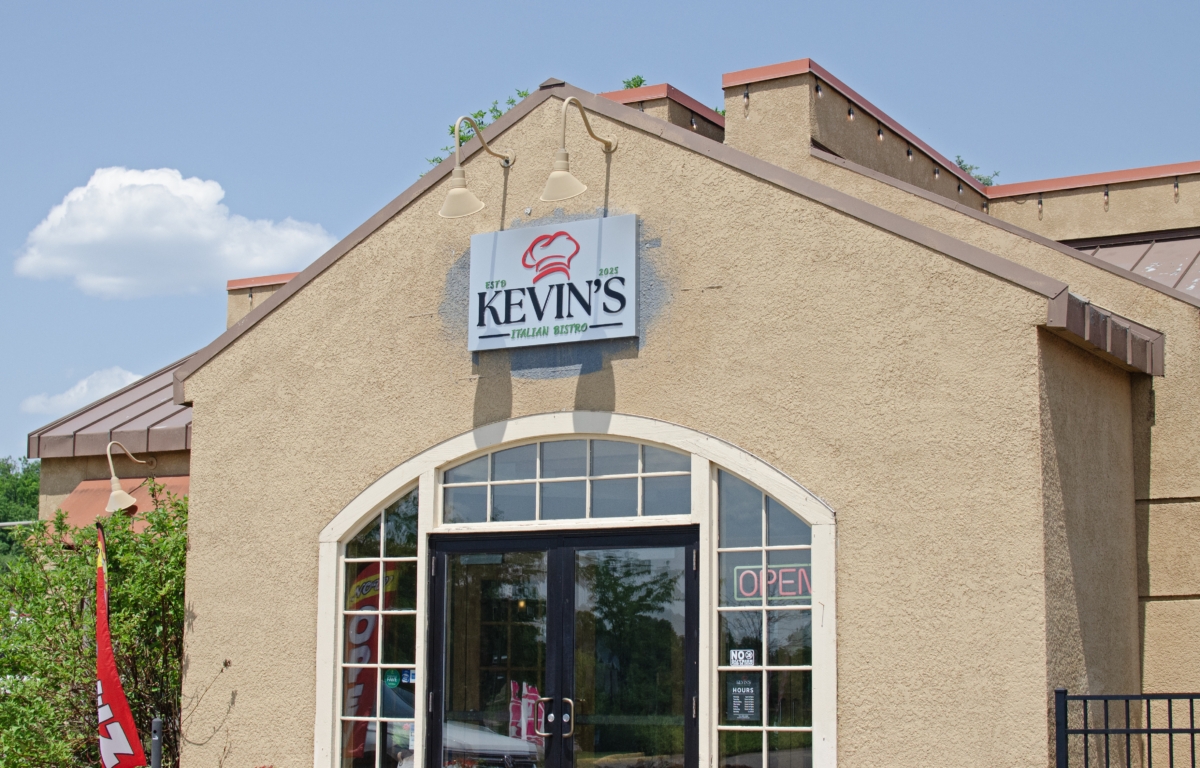 Kevin's Italian Bistro, a beige stucco restaurant, stands at 6399 City West Parkway in front of a bright blue sky with fluffy clouds.